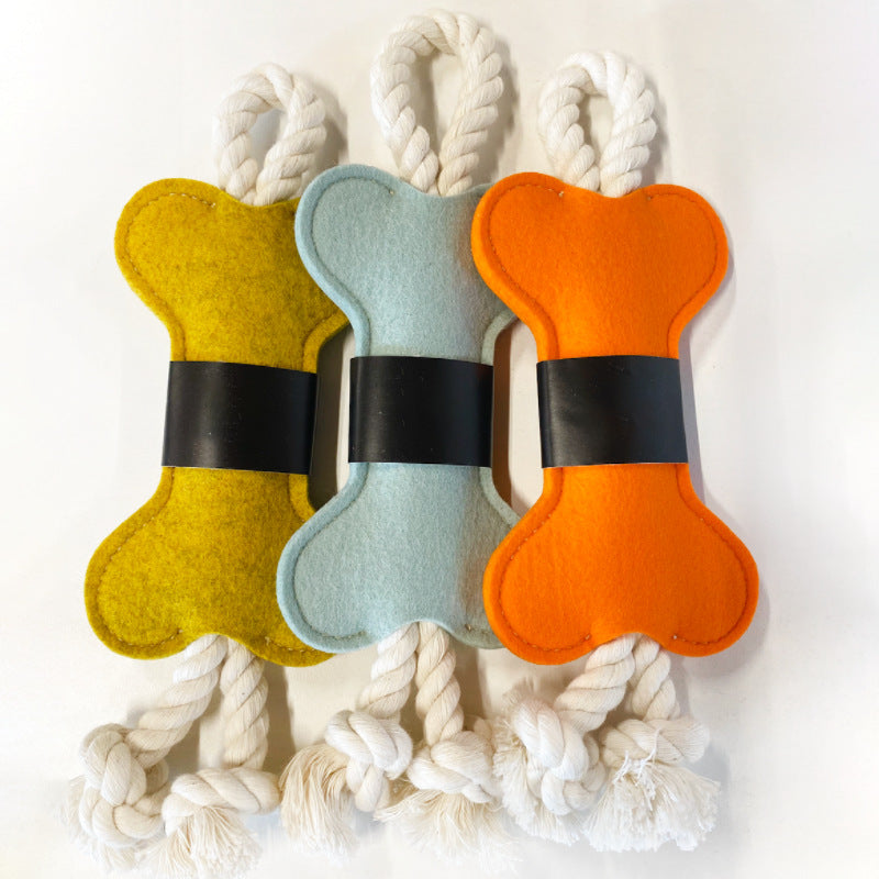 Vista en detalle de juguete con forma de hueso de fieltro para perro color beige